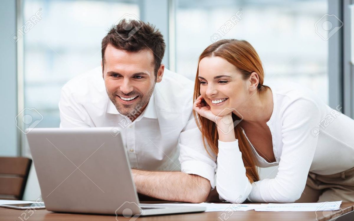 96795080-two-happy-business-people-working-on-laptop-in-office